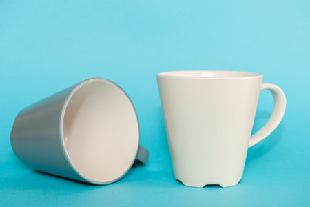 Grey and white empty coffee mugs on a light blue backgroundの写真素材