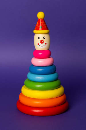 Colourful kids stacking toy on coloured background. Wooden ring stacking clown for toddlers. The stacker is standing upの写真素材
