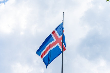 The red, blue and white Icelandic flag waving in the wind. It is a grey, cloudy summer day