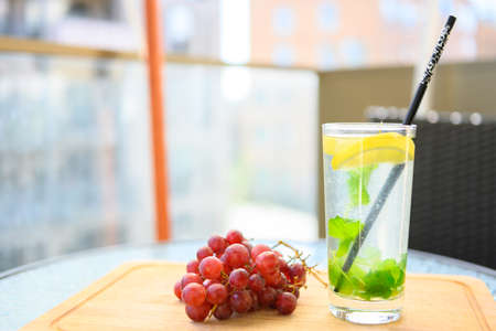Refreshing drink with lemon and Moroccan mint. Served on the terrace, together with some ripe, red grapes. It is a hot, beautiful summer day.の写真素材