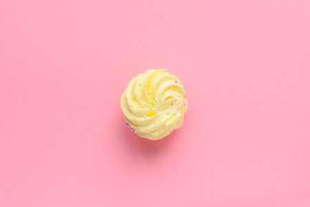 Still life of a very colorful meringues, with colored sprinkles on, placed on a pink background. A single yellow meringue is lying in the middle of the frame. Plenty of copy space around.の写真素材