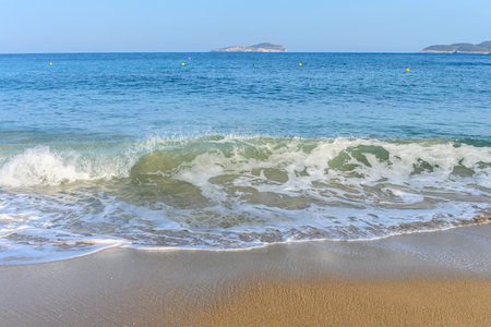 Small waves crashing at the beach in Cala San Vicente, in the northern part of Ibiza, Spain. The private owned island of Tagomago is in the background. It is a sunny spring day.の写真素材
