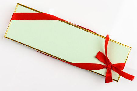 Beautiful mint green and gold gift box with a red ribbon wrapped around, on a white background. Copy space around, and space for text on the boxの写真素材