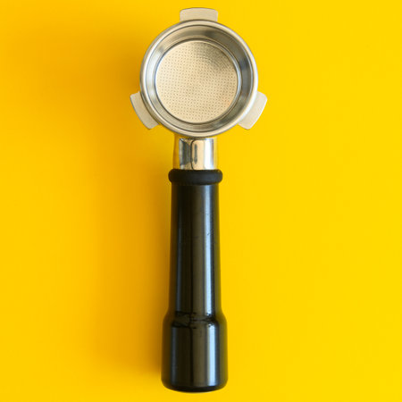 Empty espresso portafilter with a filter basket lying on a yellow background. The portafilter is lying horizontally in the middle of the frame, close up.の写真素材