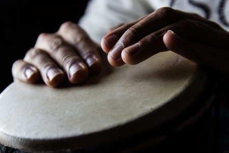 Playing African Drums in Low Key Single Light by Musician in Music Studio, West Africa.の写真素材