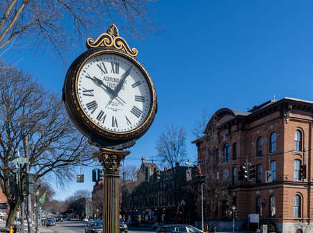 Saratoga Springs, NY - USA - Mar. 6, 2021: A landscape view of Adirondack Trust Company's doubleface street clock on Broadway. City Hall seen across the street.のeditorial素材