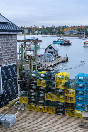 Bernard, ME - USA - Oct.15,2021: Vertical view of an old wooded shingled workshop, docks, pier, lobster traps and buoys, with fishing boats in the Bass Harbor in Mount Desert Island.のeditorial素材