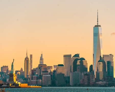 New York, NY - USA - Dec 26, 2021: Horizontal sunrise view of the Statue of Liberty in the New York Harbor, with the skyline of Manhattan, World Trade Center and Empire State building behind her.のeditorial素材