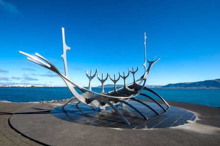ReykjavÃ­k, Iceland - July 4, 2022 Horizontal view of the Sun Voyager, a huge 1990 stainless-steel sculpture of a boat by JÃ³n Gunnar Ãrnason, set on granite beside the sea.のeditorial素材