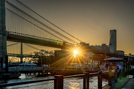 Brooklyn, NY - USA - March 26, 2023 Horizontal view of the sun rising over DUMBO section of Brooklyn and the Brooklyn Bridge. Sunrise seen from the Brooklyn Bridge Lookout.のeditorial素材