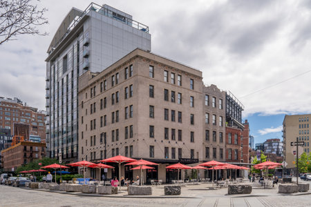New York, NY - US - May 19, 2024 A cobblestone plaza with red umbrellas, tables and chairs in the Meatpacking District, a hip commercial area on the far west side, filled with trendy restaurants.のeditorial素材