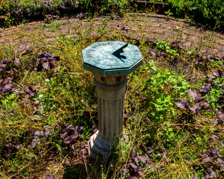 Bronx, NY - US - July 13, 2024 he BartowâPell Mansionâs sundial stands elegantly on a classic column amidst a lush, overgrown garden, blending history with natureâs untamed beauty in a serene setting.のeditorial素材