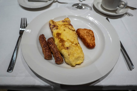 A classic breakfast plate featuring an omelet, two sausage links, and a hash brown, perfectly arranged for a satisfying morning meal.の写真素材