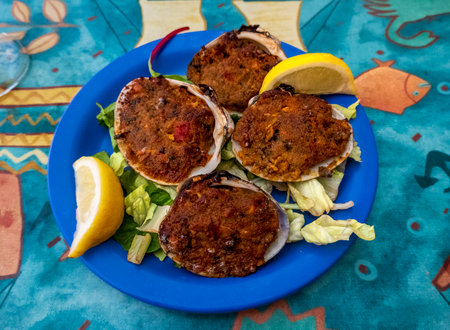 A plate of baked stuffed clams, also known as "stuffies," is garnished with fresh lemon wedges and served on a bed of lettuce. This classic seafood appetizer is a New England favorite.の写真素材