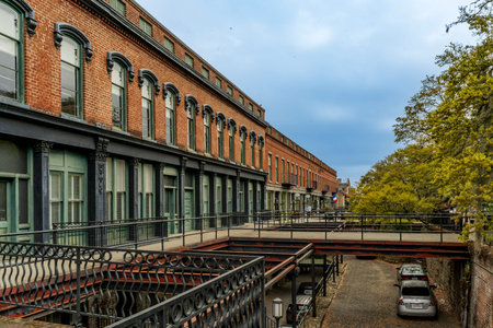 Savannah, GA - US - Mar 25, 2026 Historic Factors Walk in Savannah, GA, features multi-level brick buildings, a raised iron walkway, and cobblestone street, reflecting its rich cotton trade history.