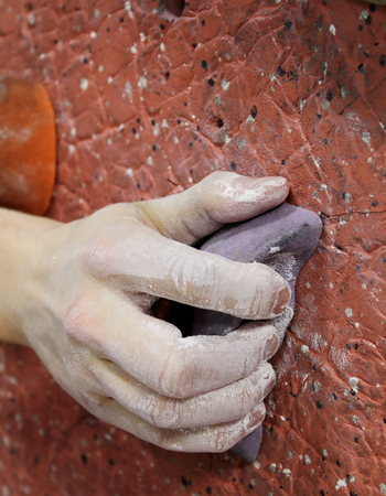 Rock Climber hand gripping purple ledge on brown wallの写真素材