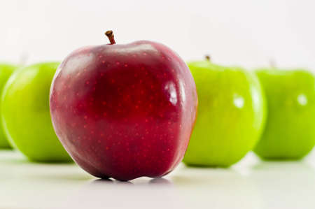 a unique red delicious apple in front of green granny smithsの写真素材
