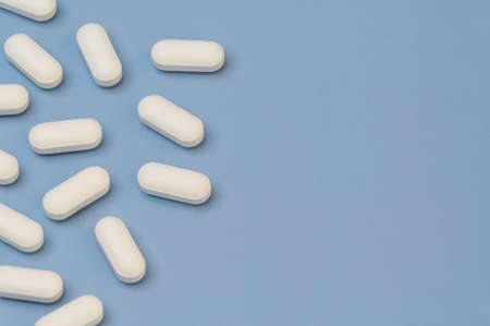 Vitamin tablets supplement on Blue background with space for writing on right of imageの写真素材