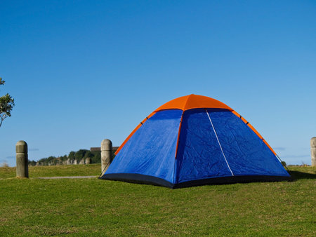 Small blue tent with an orange peak erected at beachside camping ground, Mount Maunganui, New Zealand.の写真素材