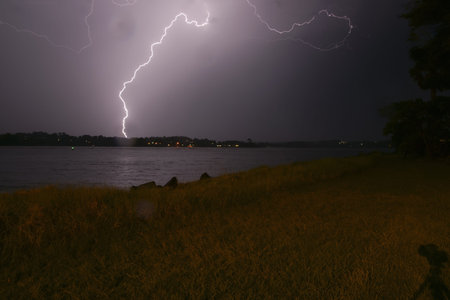 Lightning strikes across the night sky lighting the harbour and foreground.
