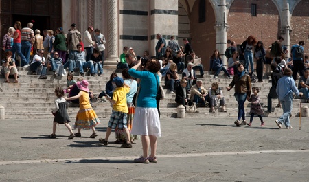 Siena, Italy, April 19 2011. Tourists outside cathedral, Duomo Santa Maria in Siena, taking photos and waiting.のeditorial素材