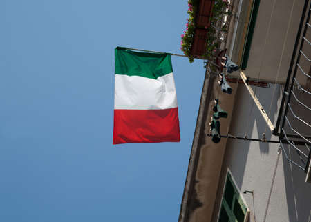 Italian flag above, against blue sky.の写真素材