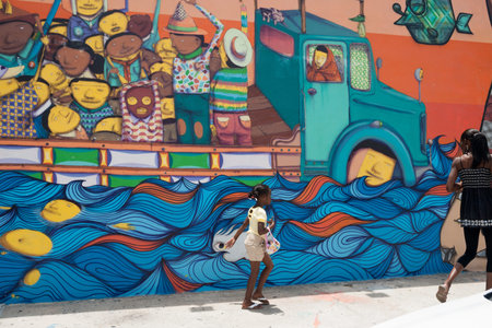 Wynward, Florida, USA, June 28, 2012- two people, a black woman and daughter pass a brightly painted wall depicting diversity.のeditorial素材