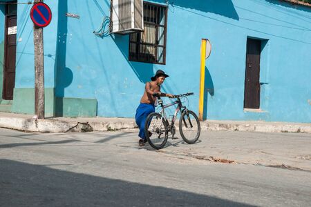 TRINIDAD, CUBA - JULY 2: Boy with bicycle crosses street in Cuban city of Trinidad, Cuba on July 2, 2012.. A typical scene showing a shirtless person in a steet of the city in south of the country.のeditorial素材