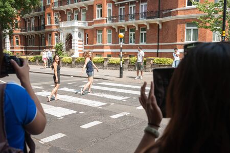 London, England; July 17, 2013; Tourists take photographs of people on the famous crossing outside Abbey Road Studios where the Beatles recorded のeditorial素材