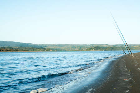 Three fishing poles at waters edge の写真素材