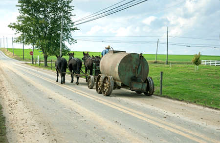 Amish horse drawn tank being pulled along a country road through farmland on October 22, 2014 in Lancaster, USA.の写真素材