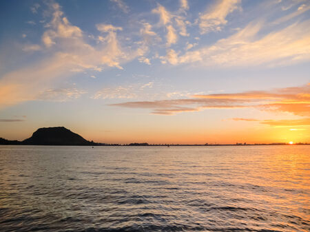 Mount Maunganui silhouetted on horizon as a golden sunrises.の写真素材