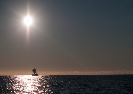 Maori sailing waka of Tauranga coast, on horizon soon after sunrise.