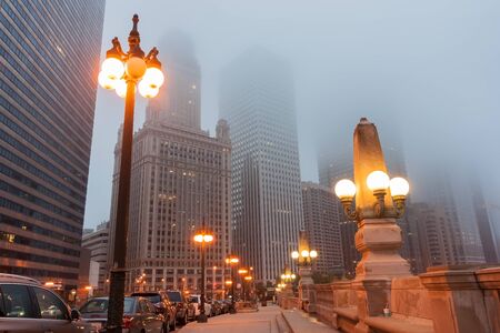 Chicago Illinois USA street as mist descends and lights come on Upper Wacker Drive with ornate lights tall buildings rising into fogの写真素材