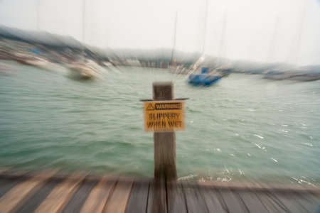 Warning og danger near harbor Slippery when wet sign in zoom blur effectの写真素材