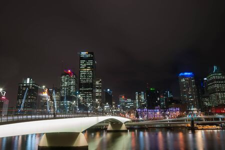 Brisbane, Australia - April 27, 2016; Brisbane Victoria Bridge iluminated against dark and city building lights and colr reflections in calm water of Brisbane Riverのeditorial素材