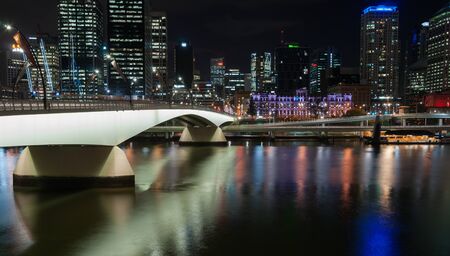 Brisbane, Australia - April 27, 2016; Brisbane Victoria Bridge iluminated against dark and city building lights and colr reflections in calm water of Brisbane Riverのeditorial素材