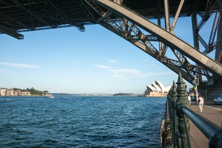Sydney Australia, January 26, 2011; Sydney opera House along harbor edge two people walking under silhouette structure of Sydney Harbor Bridge.のeditorial素材