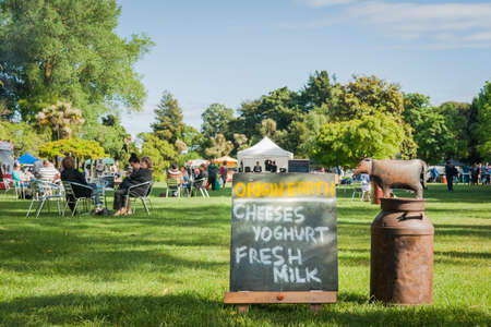 Hastings New Zealand November 13, 2011; Weekend Farmers Market sign with groups of people sitting around tables relaxing in shadeのeditorial素材