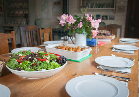 Dinner table, set with salad and food ready to be served and eaten.の写真素材