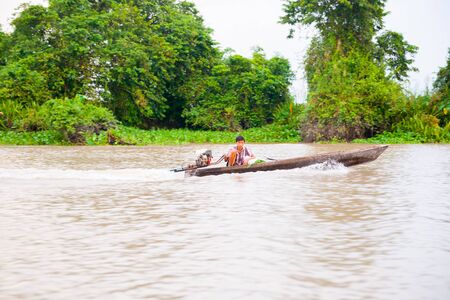 Ho Chi Minh City, Vietnam - October 12,2013; Man steers his dugout type boat along the Muddy mekong River near Ho Chi Minh City Vietnam.のeditorial素材