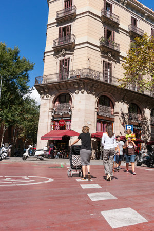 Barcelona, Spain - September 19, 2016; People cross city street  women with pushchairs walk away...