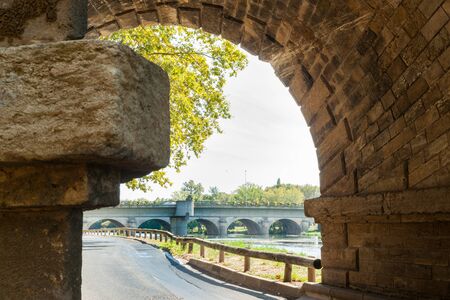 Beziers street alongside Orb River framed by stone bridge pier structureの写真素材