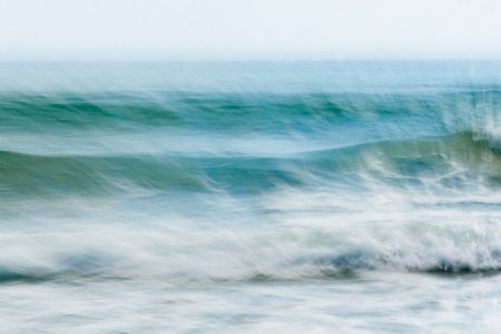 Coastal abstract motion blurred ocean waves blue tones background sea spray wind blown off surfaceの写真素材