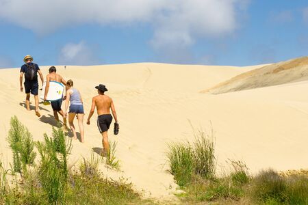 Young people head off  climbing Te Paki Sand Dunes, enormous white dunes a favorite tourist attraction and fun place Northland, New Zealandのeditorial素材