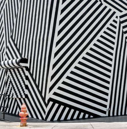 Miami, USA, June 28, 2012; modern decor pattern black and white diagonal merging stripes with small faded red water hydrant bottom left.のeditorial素材