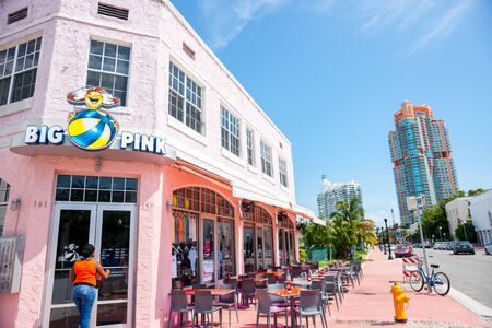 June 28, 2012, Miami USA. Woman approaches door of Big Pink retro era restaurant on Collins Avenue with empty table outside on pavement.のeditorial素材