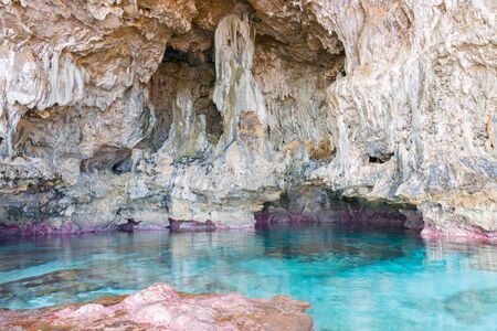 Calm turquoise colored water in coral rock pool in limestone  cave on coast of Niue.の写真素材