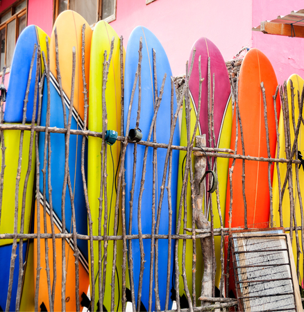 Multi-colored surf boards standing against stick fenceの写真素材