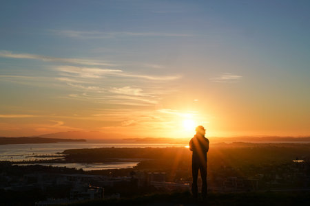 Sunrises defocused silhouette a person in bright light with abstract effecto over Auckland from top...